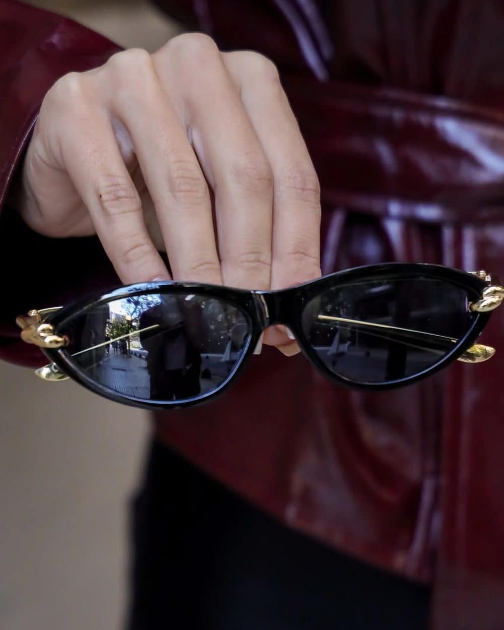 Óculos Eclipse gatinho preto com detalhe dourado, segurado na mão